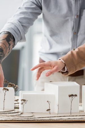 cropped view of virtual reality architects pointing with finger at model of house