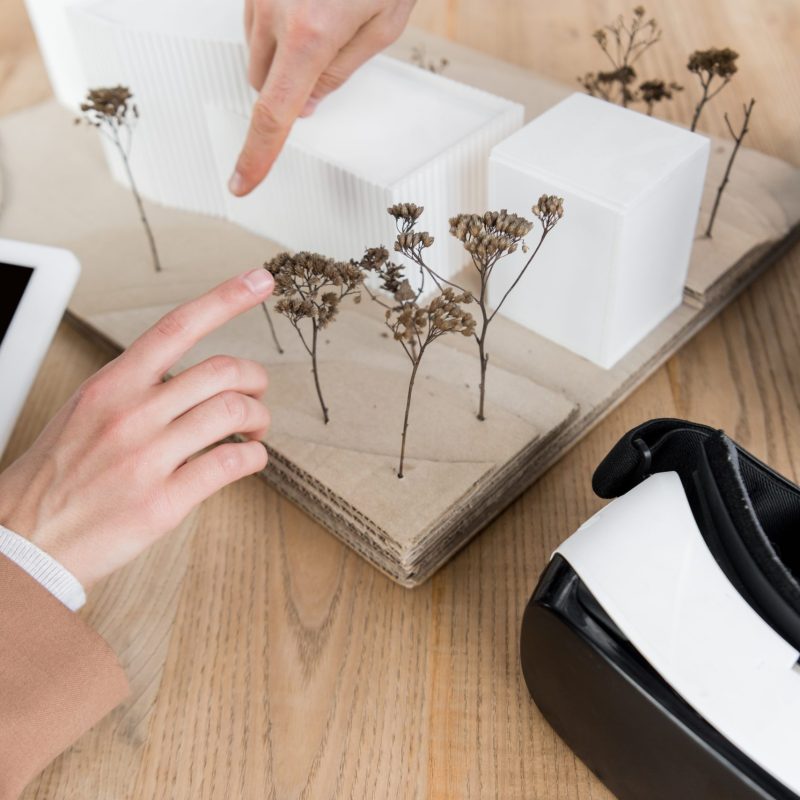 cropped view of virtual reality architects pointing with fingers at model of house